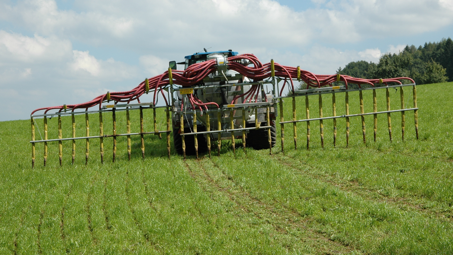 Ein Traktor, der mit einem Schleppschlauch ausgestattet ist. Durch den Einsatz von Schleppschläuchen, mit denen Güll in Streifen auf Bodenhöhe über eine Reihe von Schläuchen, die an Rampen aufgehängt sind, ausgebracht werden, können die Emissionen um 30-35 % gesenkt werden. Techniken zur Verringerung der Ammoniakemissionen bei der Ausbringung dieser Düngemittel sind seit dem1. Januar 2024 vorgeschrieben. 