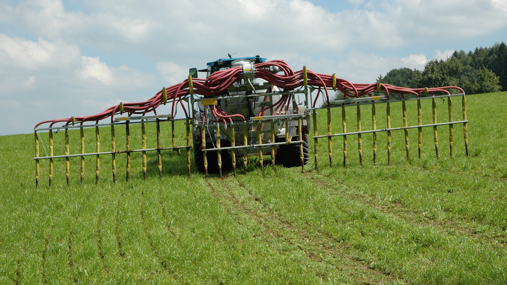 Ein Traktor, der mit einem Schleppschlauch ausgestattet ist. Durch den Einsatz von Schleppschläuchen, mit denen Güll in Streifen auf Bodenhöhe über eine Reihe von Schläuchen, die an Rampen aufgehängt sind, ausgebracht werden, können die Emissionen um 30-35 % gesenkt werden. Techniken zur Verringerung der Ammoniakemissionen bei der Ausbringung dieser Düngemittel sind seit dem1. Januar 2024 vorgeschrieben. 