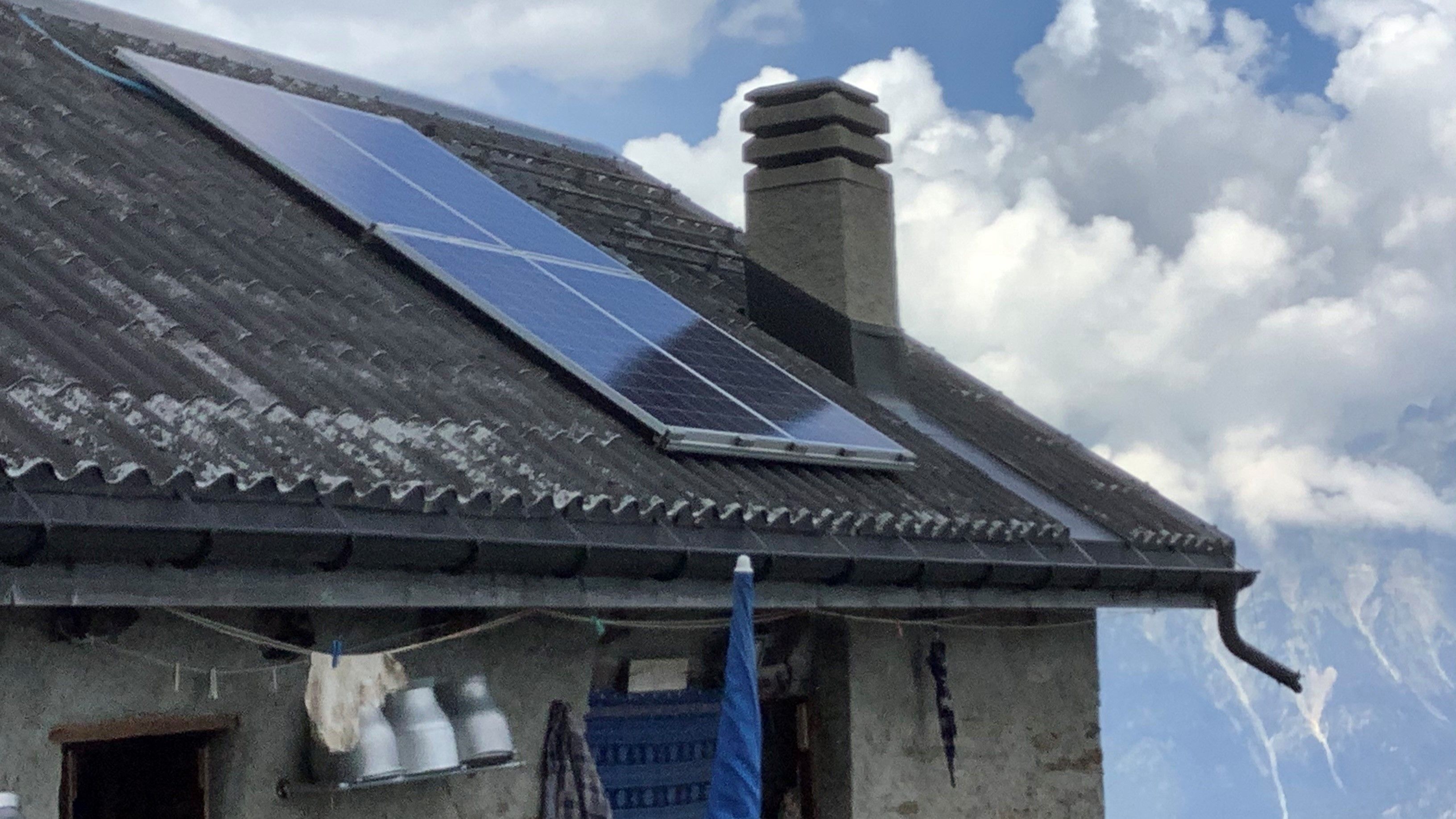 Dach eines Almgebäudes, das mit vier Photovoltaikmodulen ausgestattet ist.