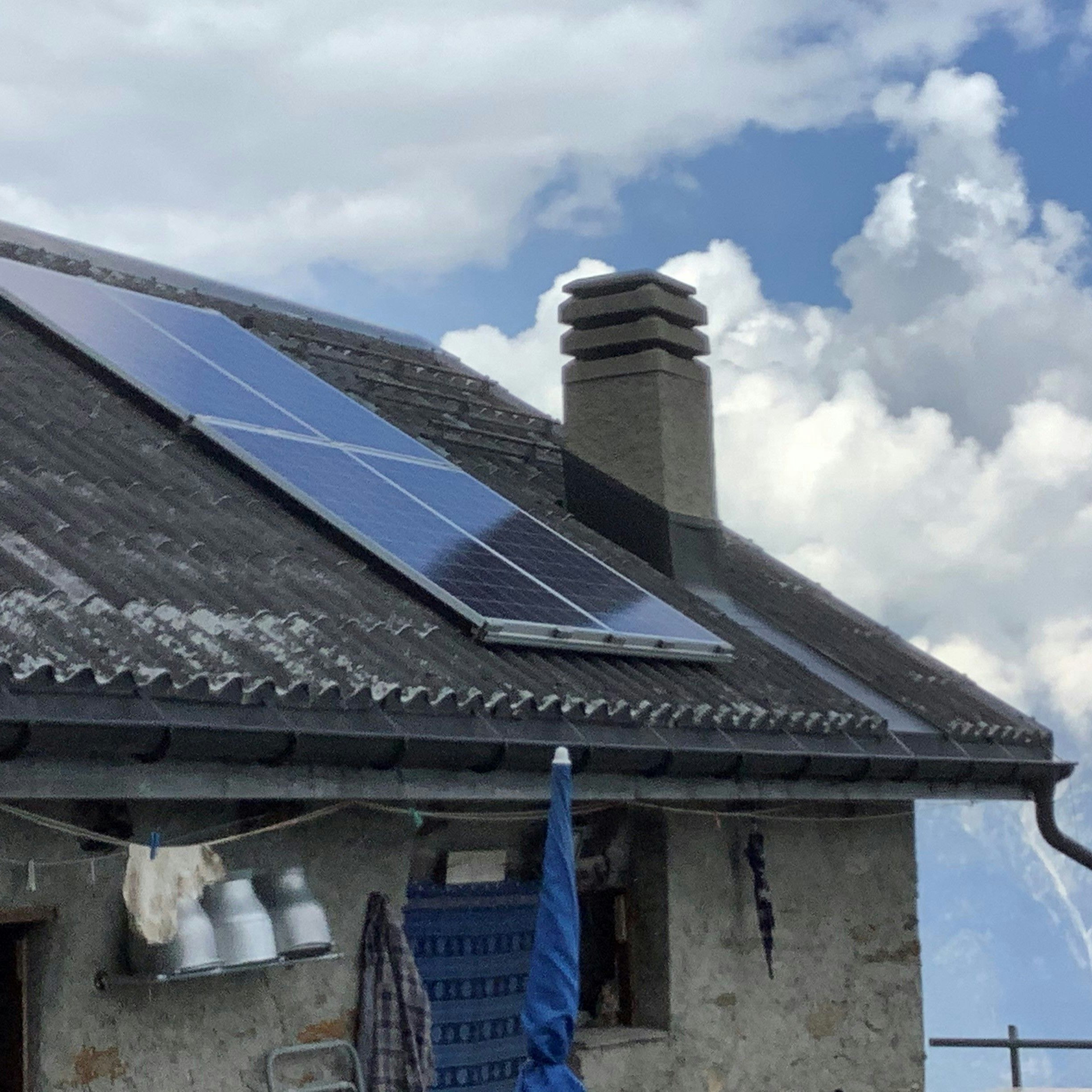 Dach eines Almgebäudes, das mit vier Photovoltaikmodulen ausgestattet ist.