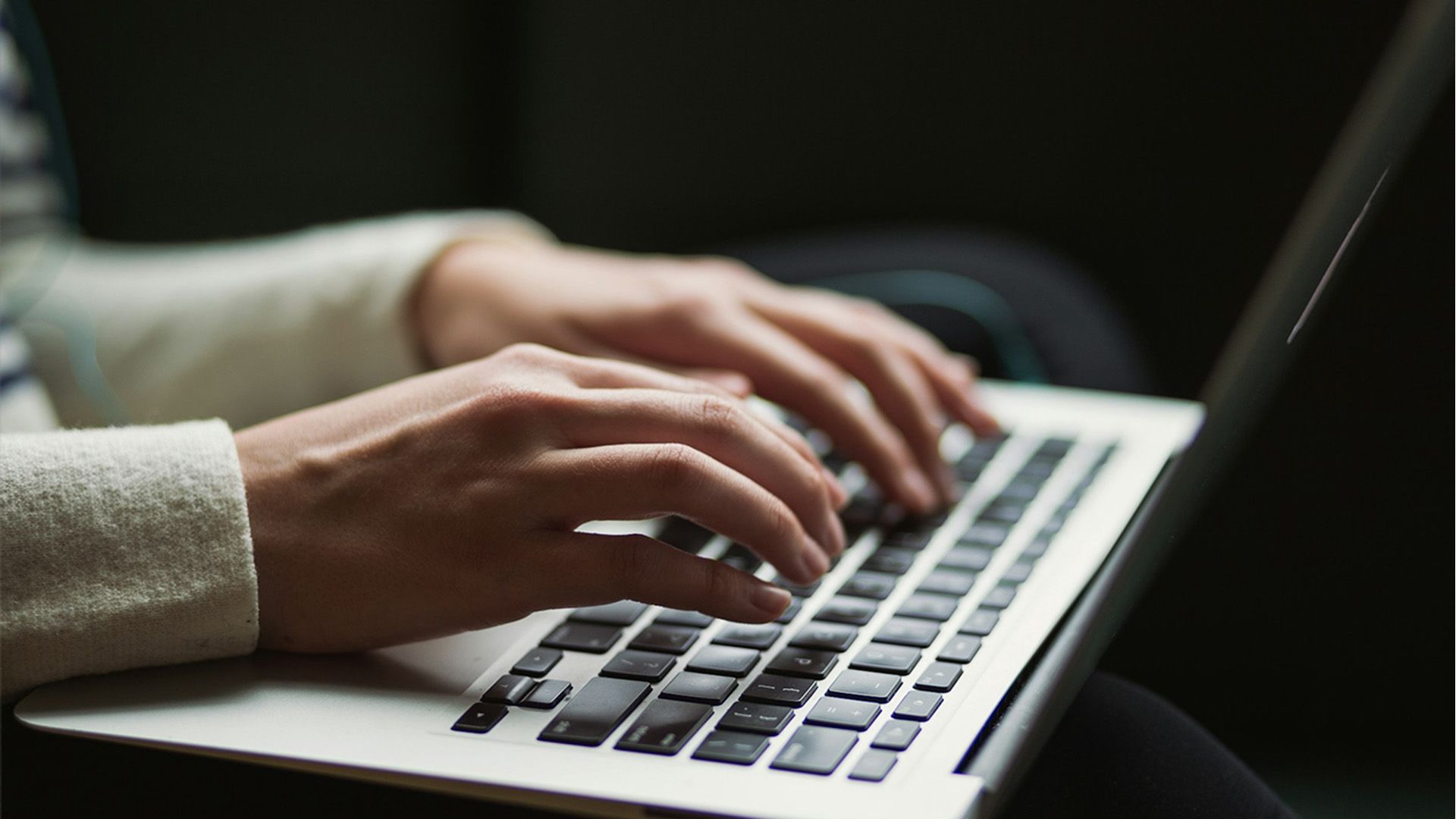 A hand typing on a laptop.