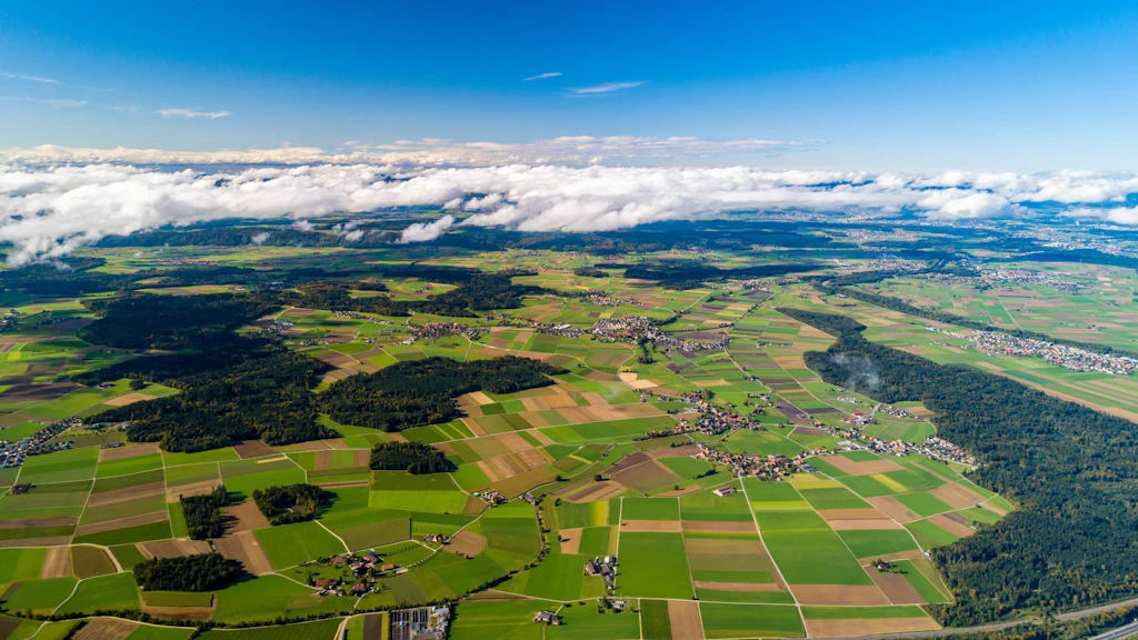 Paysage agricole comprenant des terres cultivées et quelques forêts, photographié du ciel.