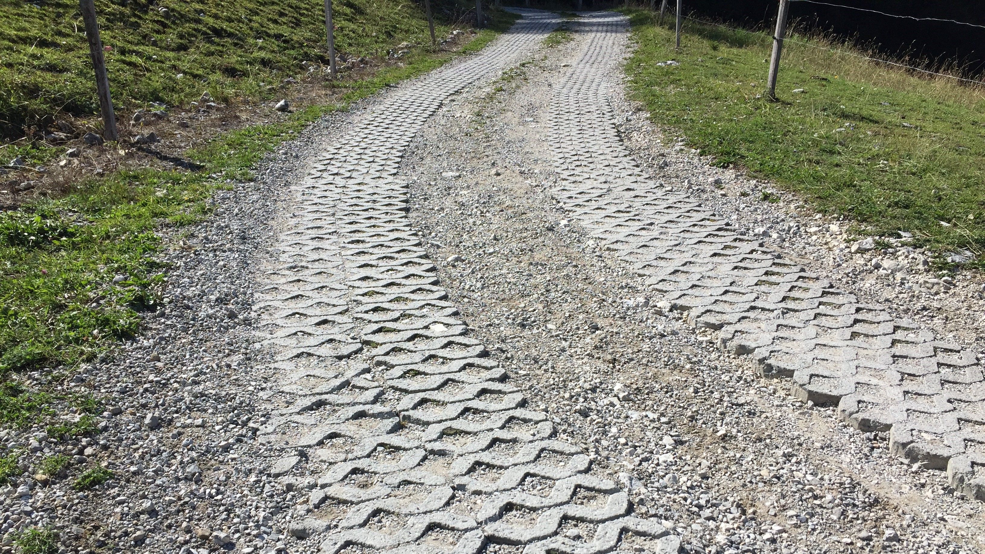 Virage à droite d’un chemin gravelé avec des bandes de roulement en grilles-gazon.