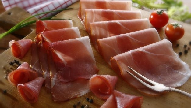 Du jambon cru coupé, prêt à être dégusté, posé sur une planche en bois