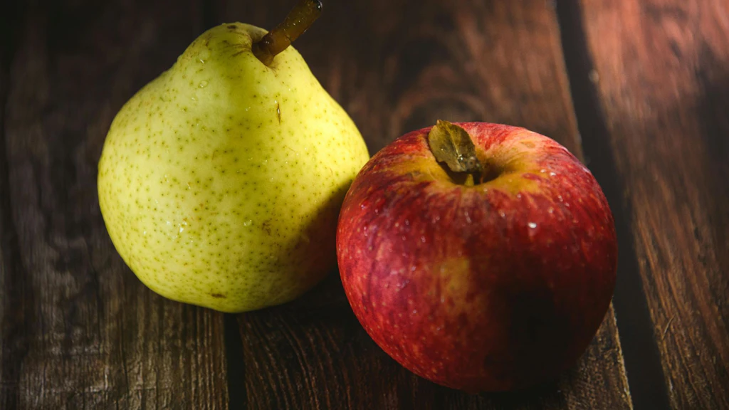 Une pomme et une poire déposées sur une table en bois