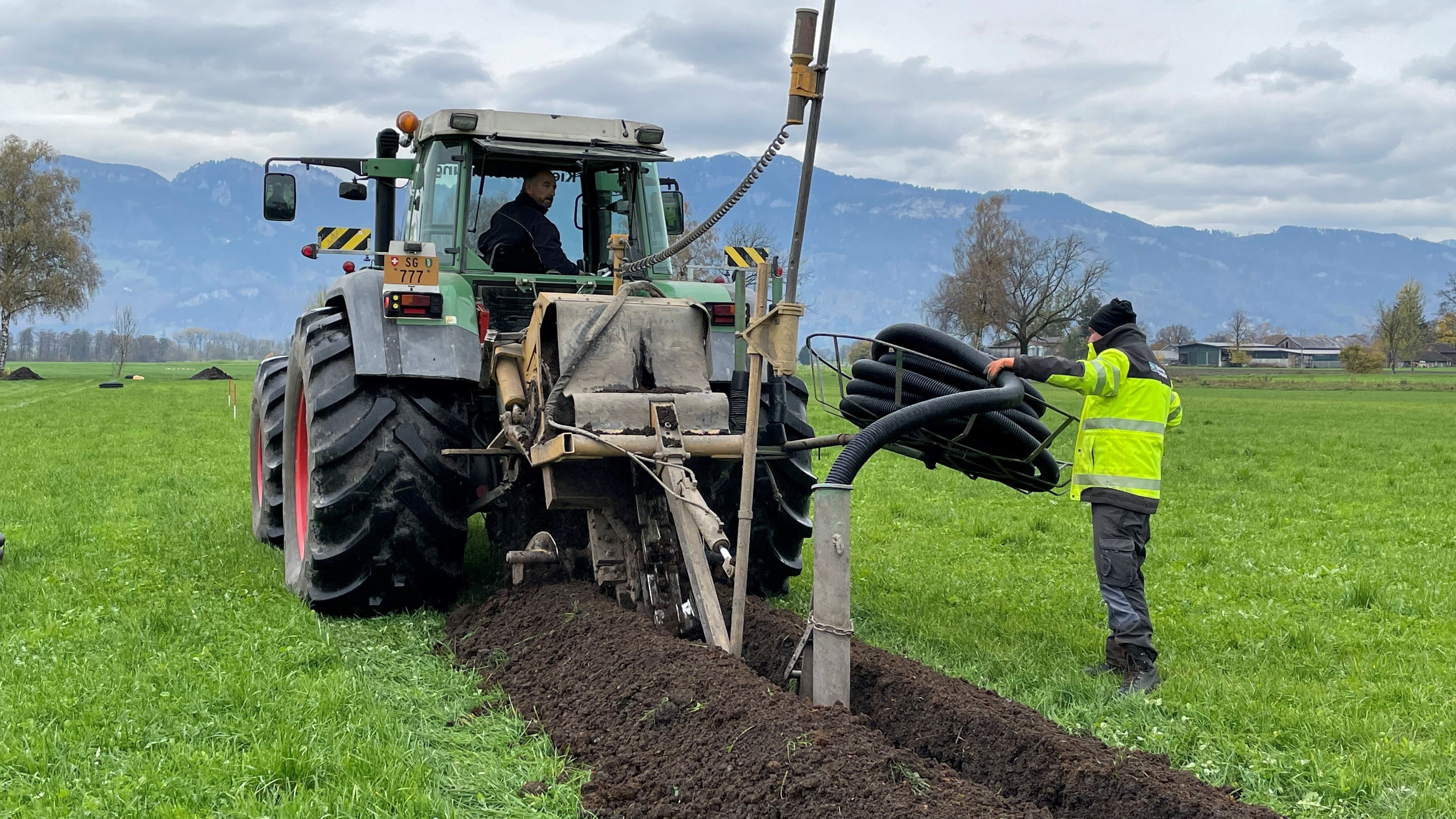 Le tracteur équipé d’une trancheuse et d’un enrouleur de tuyau pose le tuyau de drainage directement dans le sol.