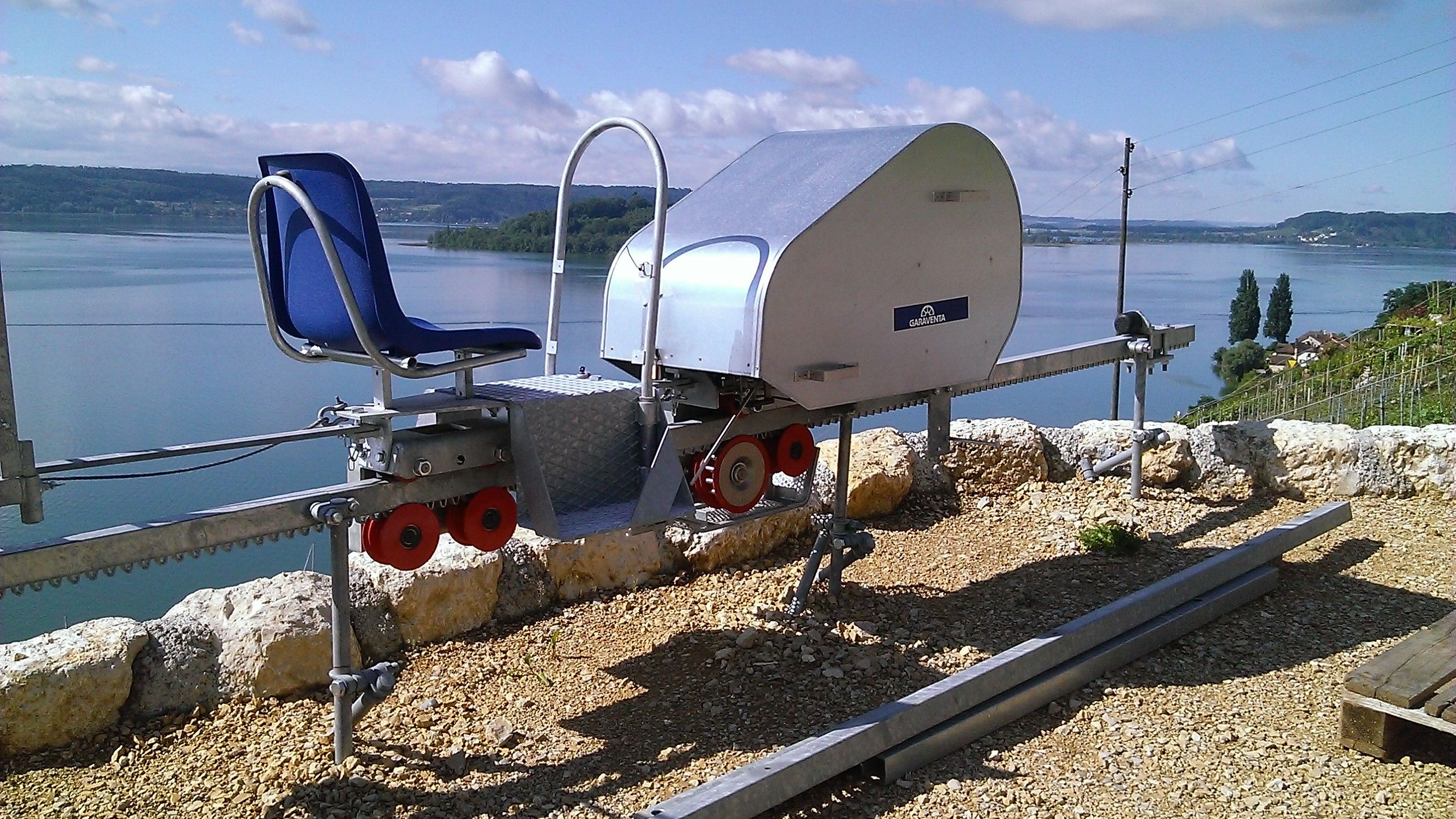 Monorail avec une seule place assise et unité de propulsion dans un vignoble avec vue sur le lac de Bienne.