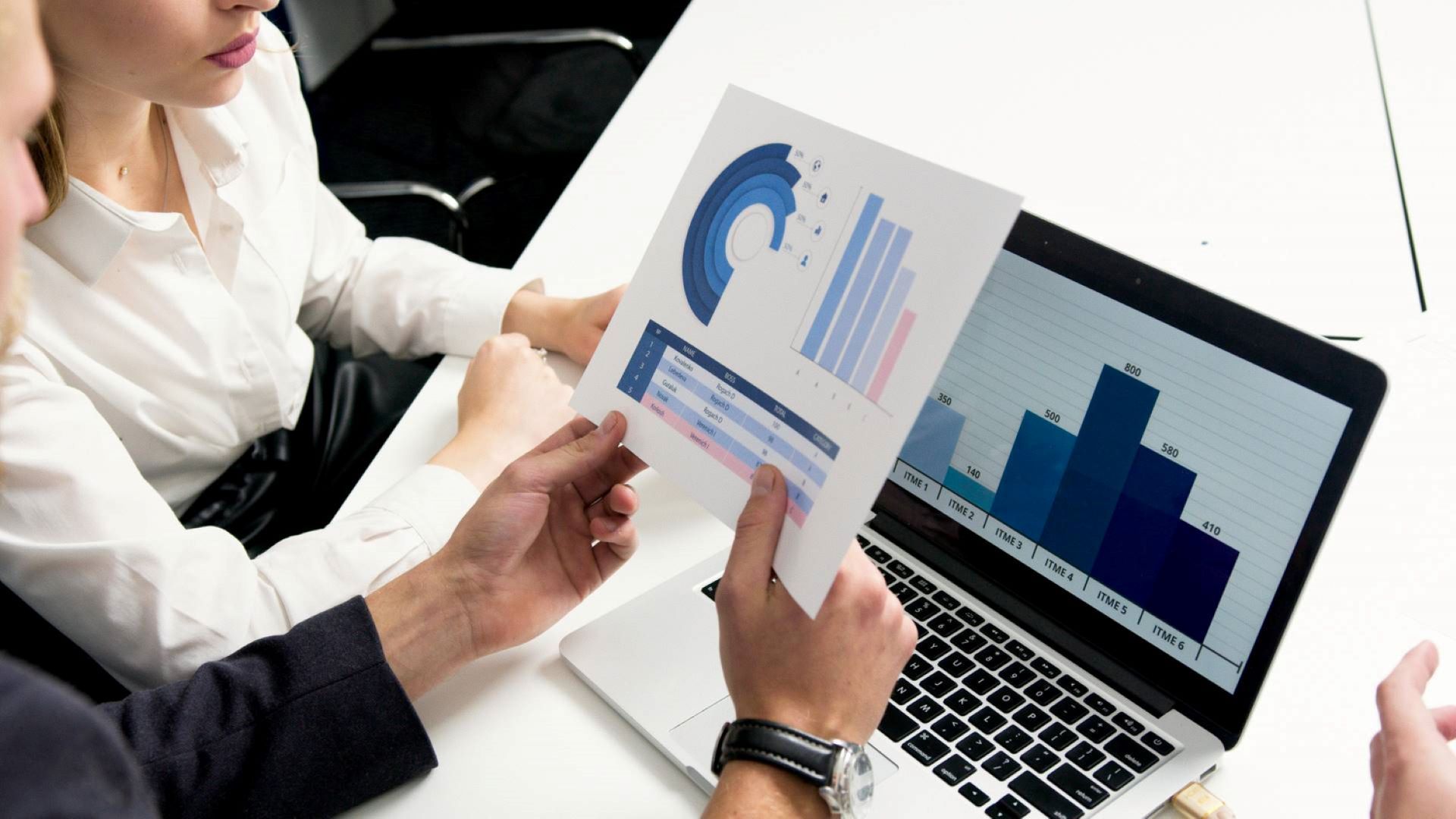 Due persone analizzano le statistiche su carta e su un computer portatile