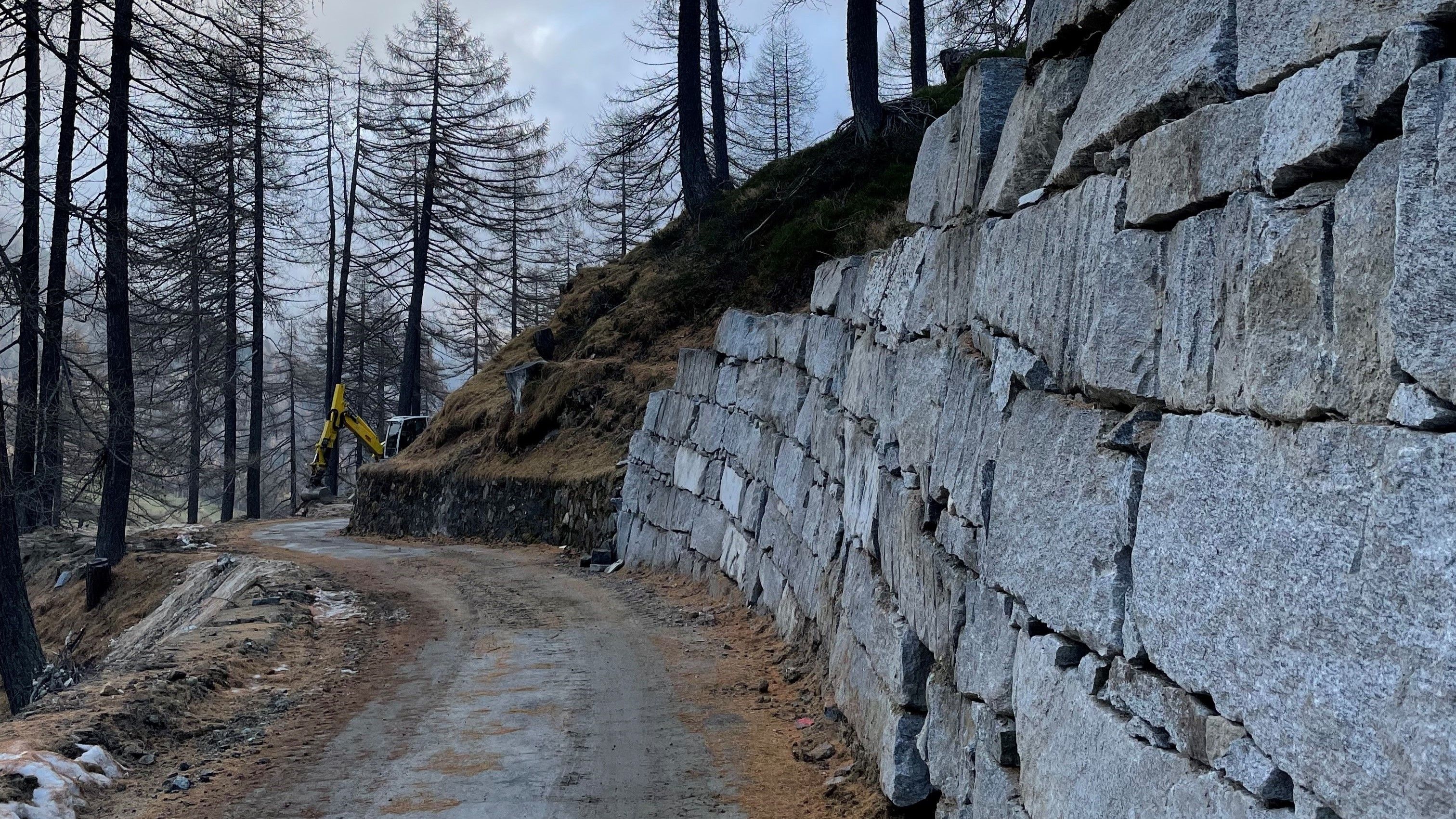 La strada in ghiaia corre parallela rispetto al pendio ed è consolidata con un muro in massi di pietra sul versante destro. Il muro in massi di pietra è costituito da 5-8 strati di massi di pietra.