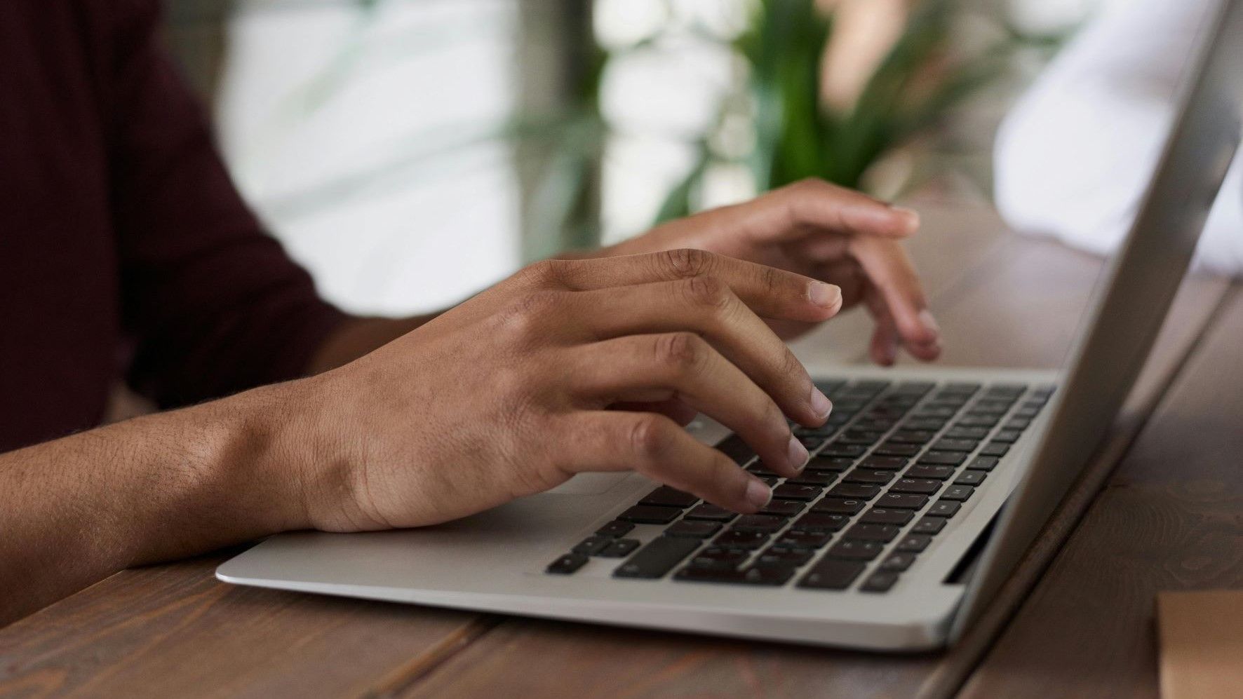 Una persona che scrive a un laptop. Primo piano delle mani.