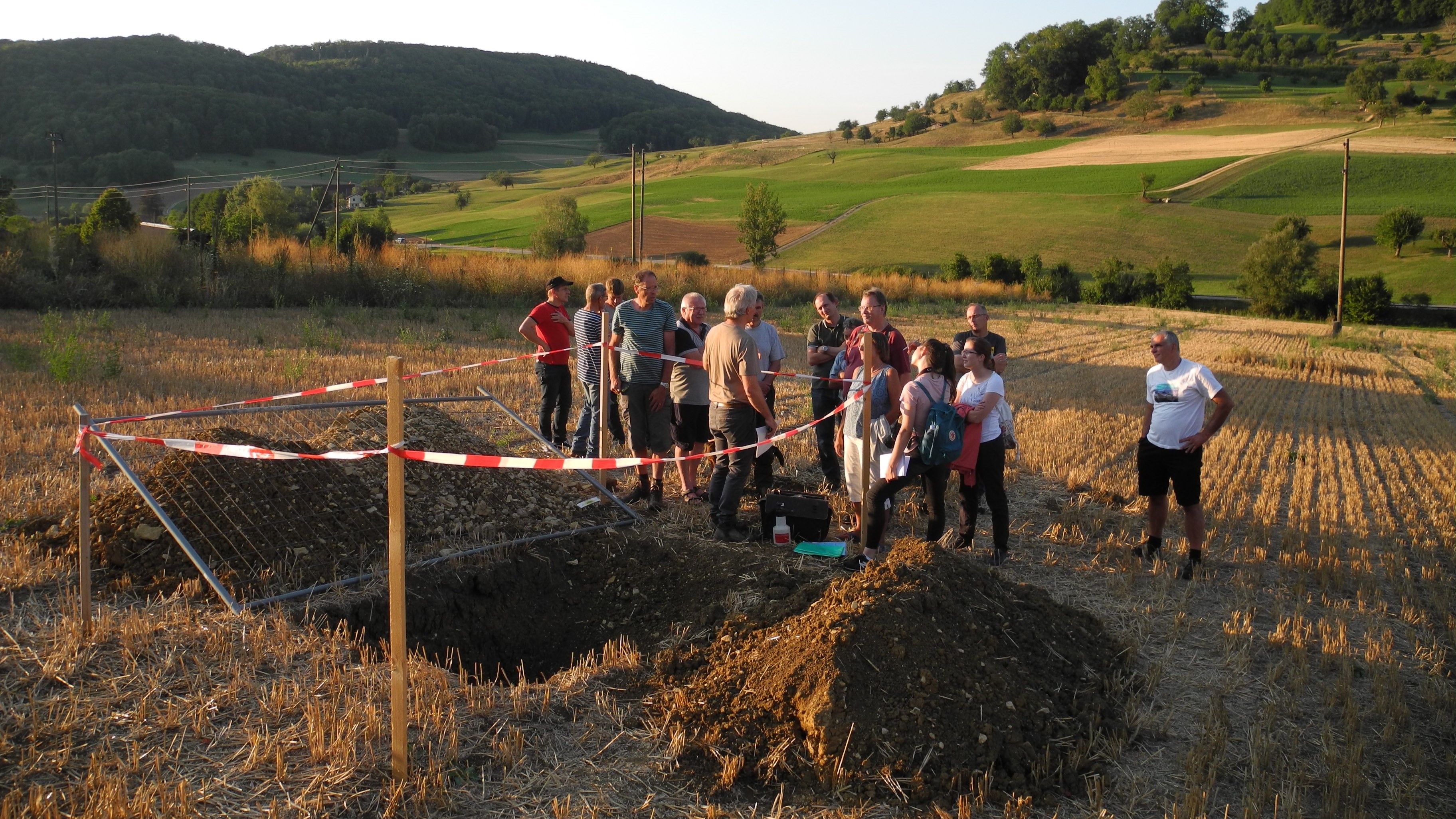 Proprietari terrieri, esperti del suolo e membri della commissione di stima osservano gli strati del suolo in un campo su cui è già stato effettuato il raccolto.